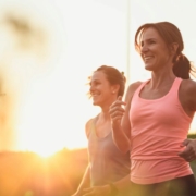 Deux femmes courant au coucher du soleil, sourire aux lèvres.
