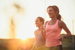 Deux femmes courant au coucher du soleil, sourire aux lèvres.