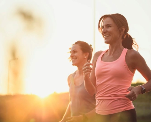 Deux femmes courant au coucher du soleil, sourire aux lèvres.