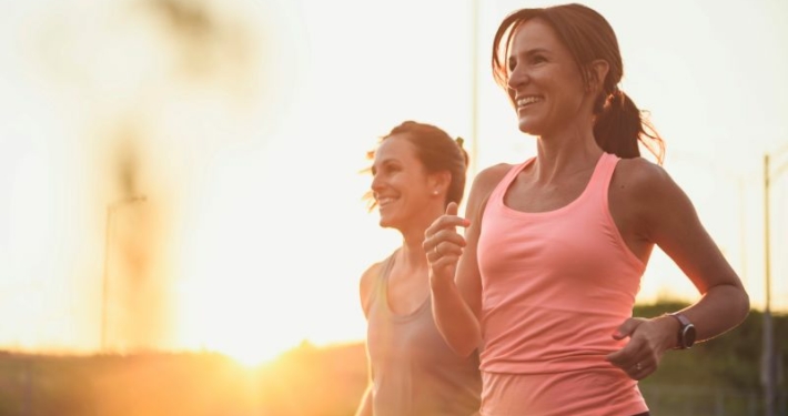 Deux femmes courant au coucher du soleil, sourire aux lèvres.