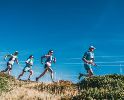 Quatre coureurs élancés sur un sentier, vue en contre-plongée.