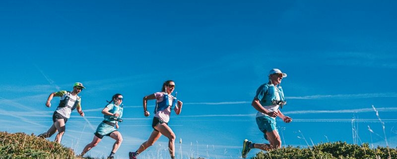 Quatre coureurs élancés sur un sentier, vue en contre-plongée.
