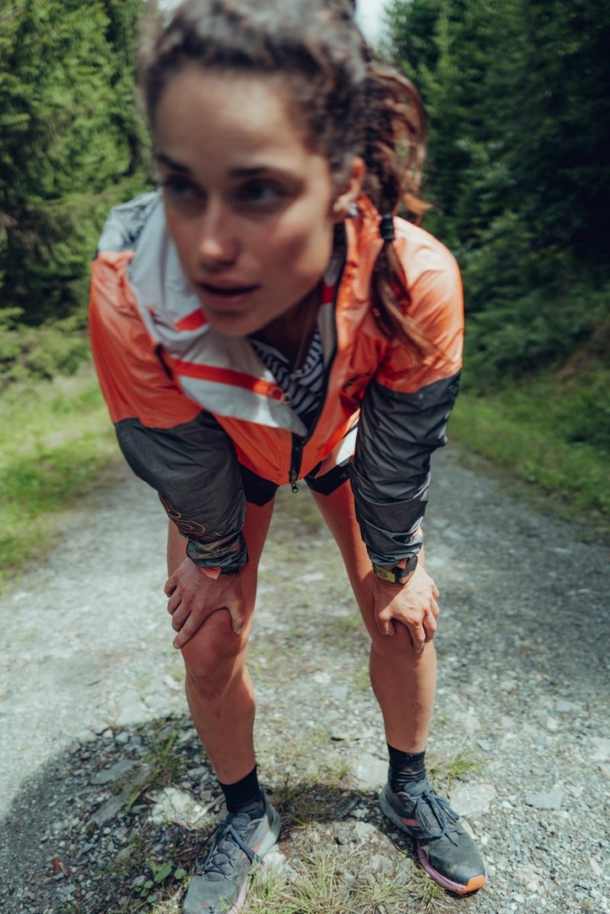 Sportive les mains appuyées sur ses genoux, elle semble essoufflée.