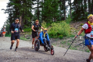 Un participant en fauteuil tout-terrain assisté par un "Helping Runner", lors de la MDS Crazy Loops.