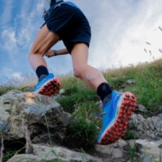 Chaussure trail Rossignol Vercors bleue, portée par un traileur alors qu'il évolue sur un sol rocheux.