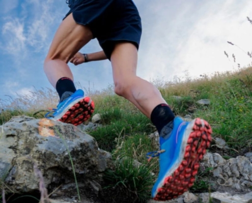 Chaussure trail Rossignol Vercors bleue, portée par un traileur alors qu'il évolue sur un sol rocheux.
