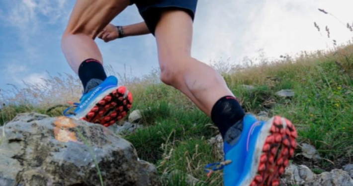 Chaussure trail Rossignol Vercors bleue, portée par un traileur alors qu'il évolue sur un sol rocheux.
