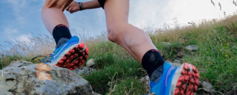 Chaussure trail Rossignol Vercors bleue, portée par un traileur alors qu'il évolue sur un sol rocheux.